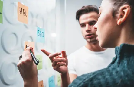 Professionals reviewing notes on a glass wall